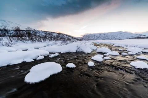 Water stream with rocks in a winter landscape in twilight. Stock Photos