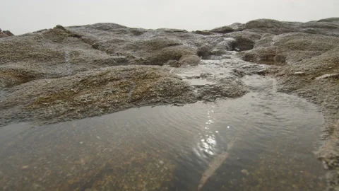 Water streaming on the rocks of the beachfront in good weather, in Spain Stock Footage 230098735