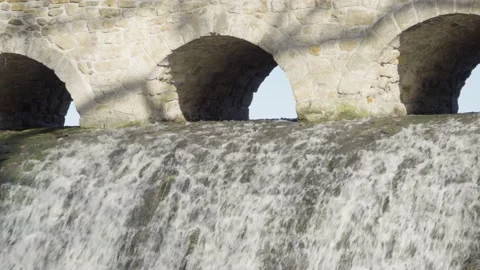 Water streams down under a low bridge in a rural area on a sunny day - front 動画素材 138202882