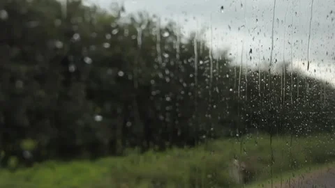Water streams down the window of a moving bus with a roadway and roadside area v Stock Footage 340890371
