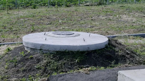 Water supply system access point, featuring a circular concrete cover set on a Stock Footage 312739222