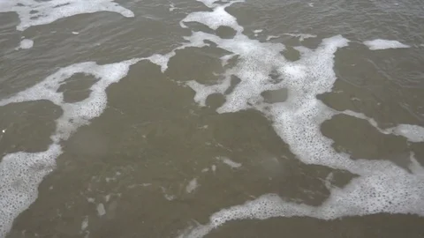 Water surf on sandy beach at stormy windy day closeup 16x super slow motion Stock Footage 84232371