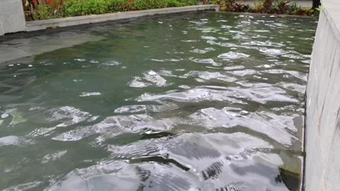 The water surface cascades down and reflects the light from the outdoor pool Stock Footage 304064539