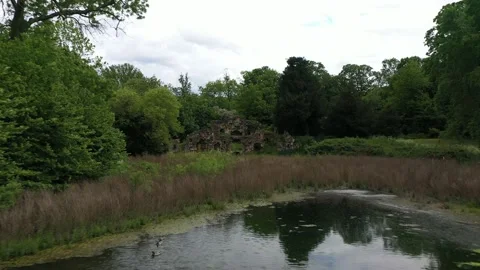 Water surface lined with trees in park, old ruined wall Stock Footage 155820975