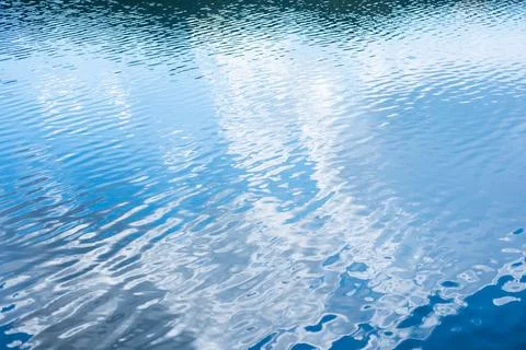 Water surface with reflecting sky creating a vibrant blue ripple pattern Foto stock