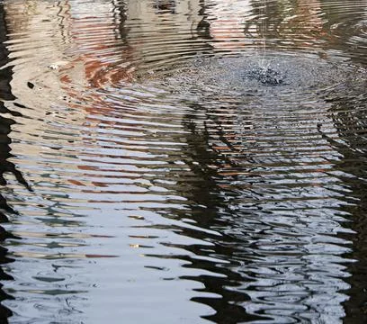 Water surface rippled by a stream  falling from a fountain Stock Photos