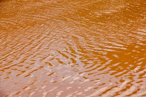 The water surface of the river is orange. Light brown river background. Silty Stock Photos