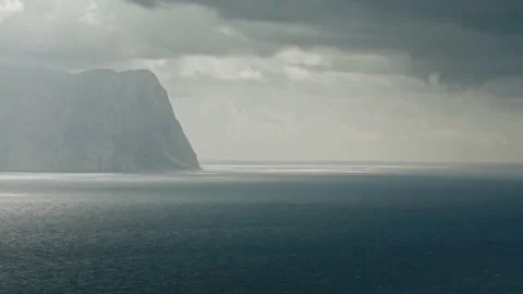 Water surface of the sea, in the background a rock surrounded by fog, rays of Stock Footage 217725169
