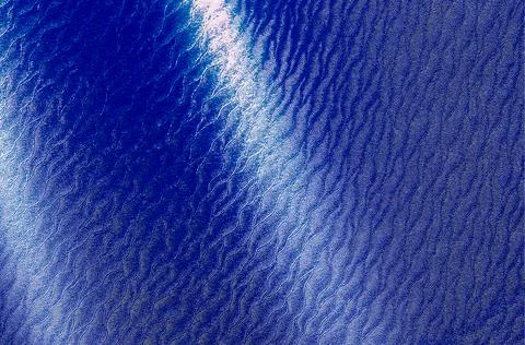 Water surface texture with blue waves and sunlight reflections. Calm liquid.. Stock Photos