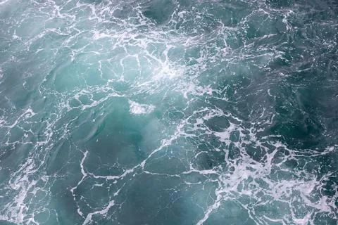 Water surface. Wake waves and foam on the blue sea water Stock Photos