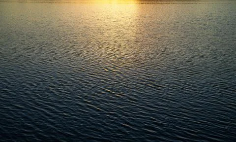 Water surface with waves under the rays of the setting sun. Stock Photos