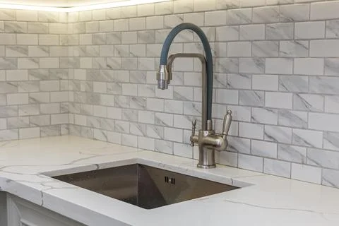 A water tap and a rectangular sink in the kitchen room. Stock Photos