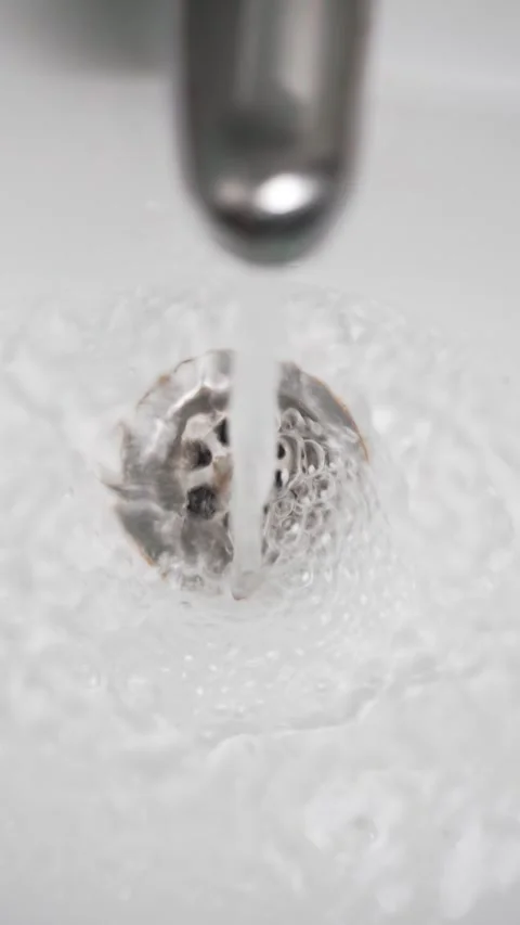 Water from the tap flows into the drain hole of washbasin Stock Footage 310539652