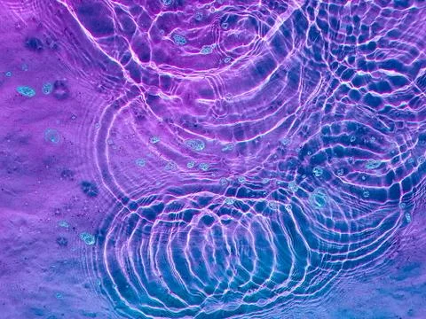 Water texture with circular streaks on the surface, bubbles and sun glare. Co Stock Photos