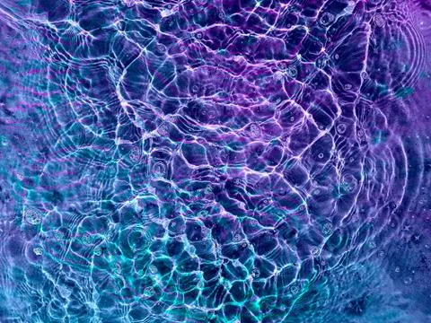 Water texture with circular streaks on the surface, bubbles and sun glare. Co Stock Photos