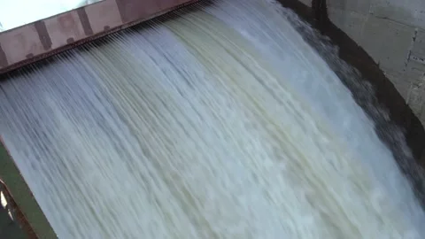 Water through dam at high speed. Water jets from under an iron beam. Water under Stock Footage 165105804