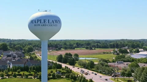Water tower and traffic circle drone rotating shot 70mm Maple Lawn, MD Stock Footage 336698493