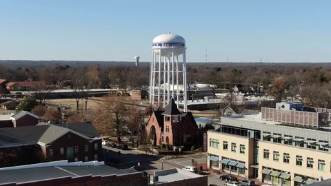 Water Tower Rising Over a Brick Church and Rooftops in Bentonville Vídeo Stock 121112042