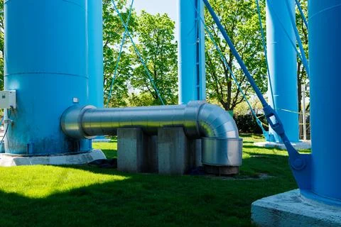 Water tower structure with large pipe and blue towers under bright sunlight.. Stock Photos