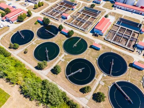Water treatment facility with large circular tanks and buildings during the d 스톡 사진
