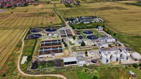 Water treatment facility in an open field near city buildings Stockbeeldmateriaal 339059172