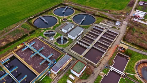 Water treatment facility operates in open land with several tanks and processing Stock Footage 335411694
