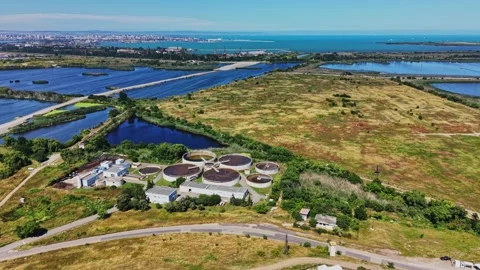 Water treatment facility surrounded by fields and water bodies near city Stock Footage 339058230