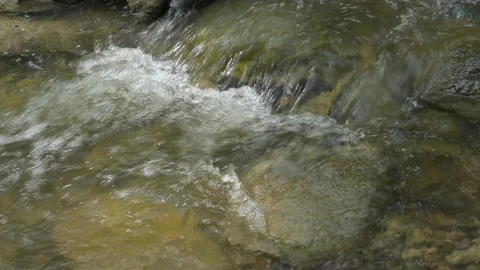 Water tumbles over a small waterfall and through boulders. Bubbles are forming  Stock Footage 155076806