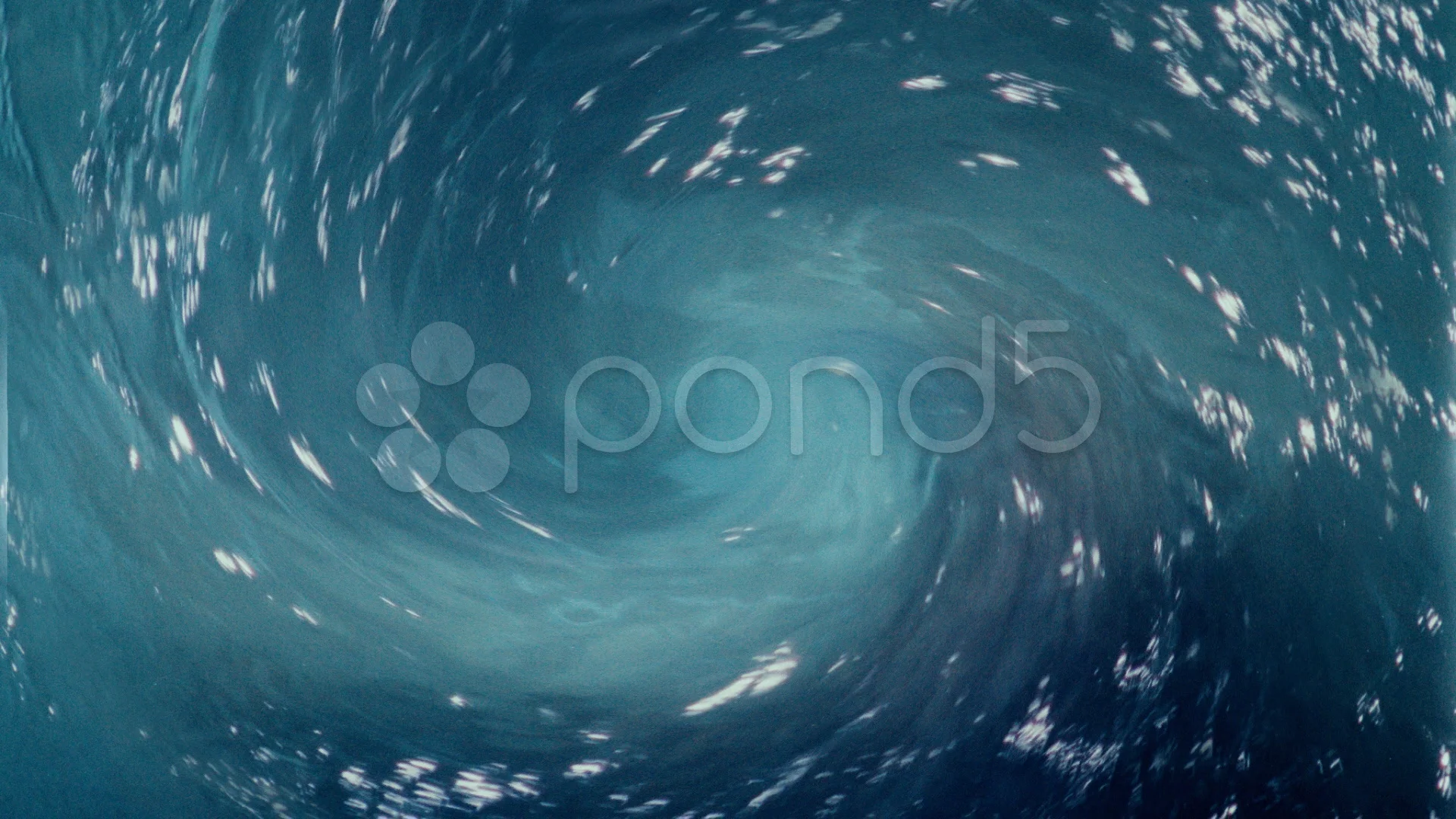 The water swirls into a whirlpool. The water is blue and clear. The wave  takes the
