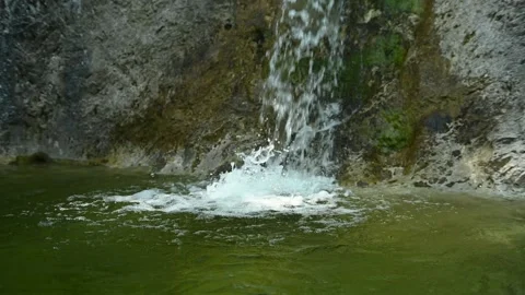 Water from a waterfall is falling into a pool with green water (slow motion) Video stock 211761066