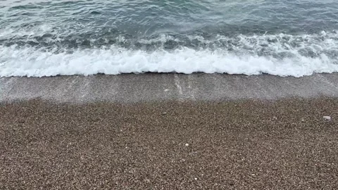 Water waves on pebble beach. Calm transparent sea wave rolling on small crushed Stock Footage 301507708