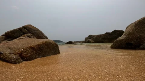 The water from the waves rolls on the sand between the stones. Stock Footage 242167299
