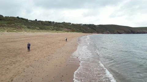Water waves with sandy beach and people , green landscape in background Video stock 185920077