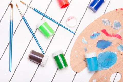 Watercolor and tempera with different paint brushes on a white wooden background Stock Photos