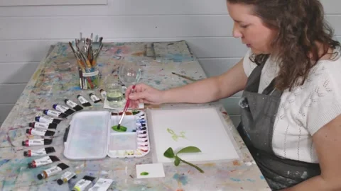 Watercolor painter adding green paint to water Stock Footage 313971132