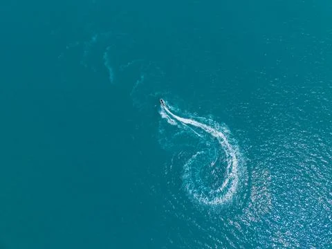 Watercraft moves quickly in a circular path across the blue ocean during a .. Stock Photos