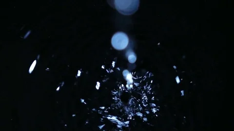 Waterdrops from blur to focus falling into dark water in extreme slow motion. Vídeos de archivo 74387027