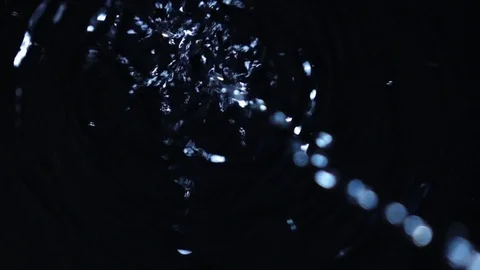 Waterdrops from blur to focus falling into dark water in slow motion. Vidéo 77021698
