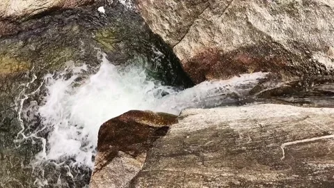 Waterfall from above, water stream flanked by large grey granite rocks Stock Footage 248378928