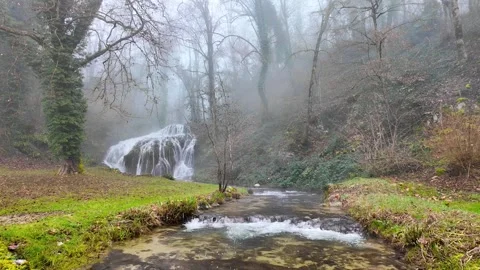 A waterfall and a river flowing from the rocks in the morning fog in the forest 動画素材 275245525