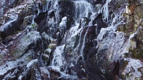 Waterfall and river flowing through a snowy and frozen mountain landscape. Stock Footage 326794704