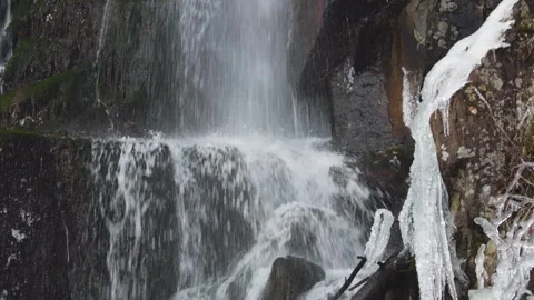 Waterfall and river flowing through a snowy and frozen mountain landscape. Stock Footage 326794723