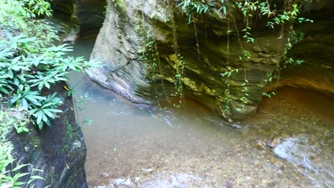 Waterfall and stream flowing through rock layers and cliff Stock Footage 221970775