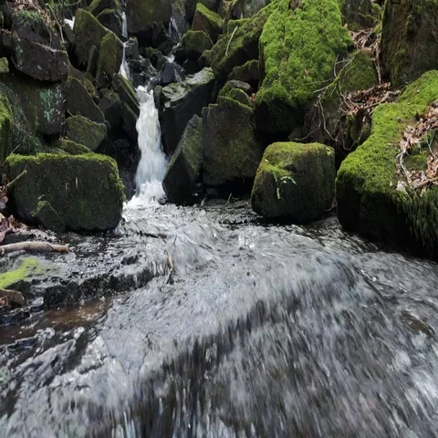 Waterfall in background with large rocks and boulders as water flows past cam Stock Footage 69524010