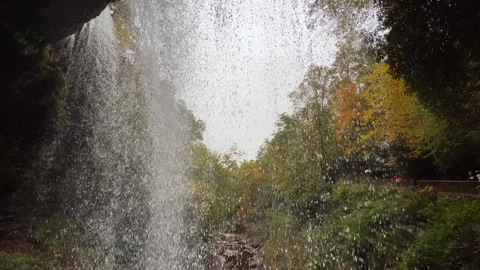 Waterfall from behind tilting down from top to landing Stock Footage 254612450