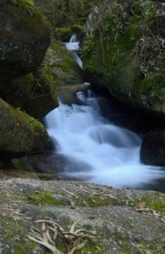 Waterfall between mossy rocks Stock Photos