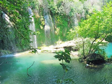 Waterfall cascade falling into blue lagoon Stock Photos