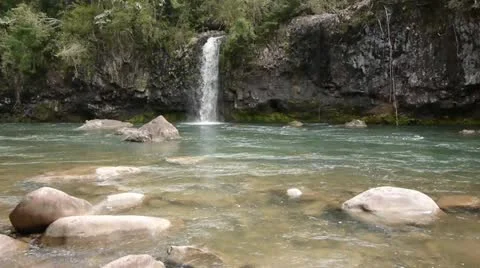 Waterfall cascades into a flowing river Stock Footage 11235917