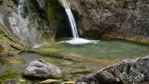 A waterfall cascades into a natural pool formed by a mountain stream Stock Footage 211468202
