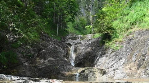 A waterfall cascades over rocks in a mountain forest Stock-Footage 212746194